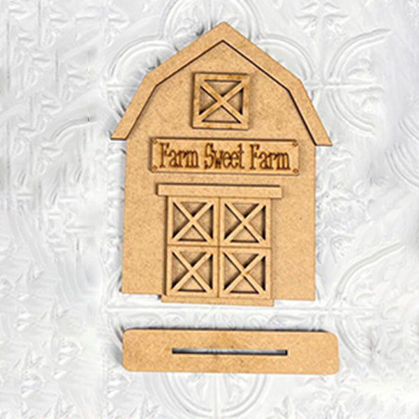 A rustic charm fills this wooden, barn-shaped shelf sitter from Janet's Craft Corner, with "Farm Sweet Farm" elegantly engraved on the front. Featuring crossed windows and a rectangular slot at the bottom, its textured white background enhances your farmhouse aesthetic beautifully.