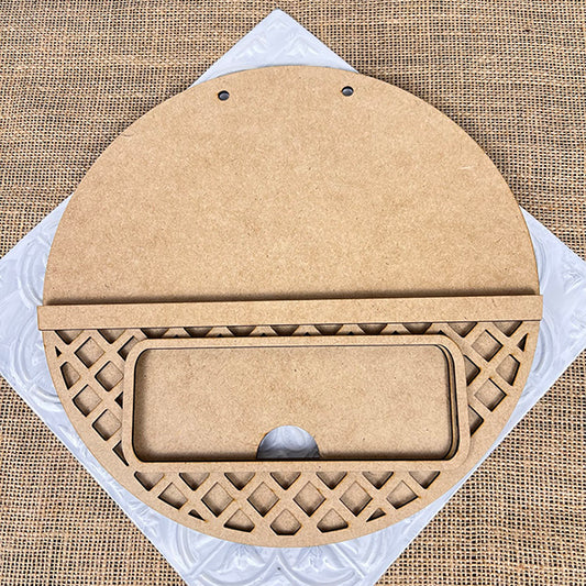 This product from Janet's Craft Corner, called the Interchangeable Sign with Interchangeable Insert, is a round wooden craft plaque featuring a rectangular compartment and lattice pattern on the bottom half, set against a textured burlap background with a square white tile. Ideal for creative projects like a Hand-Painted DIY Craft Kit, it includes two small holes at the top for hanging.