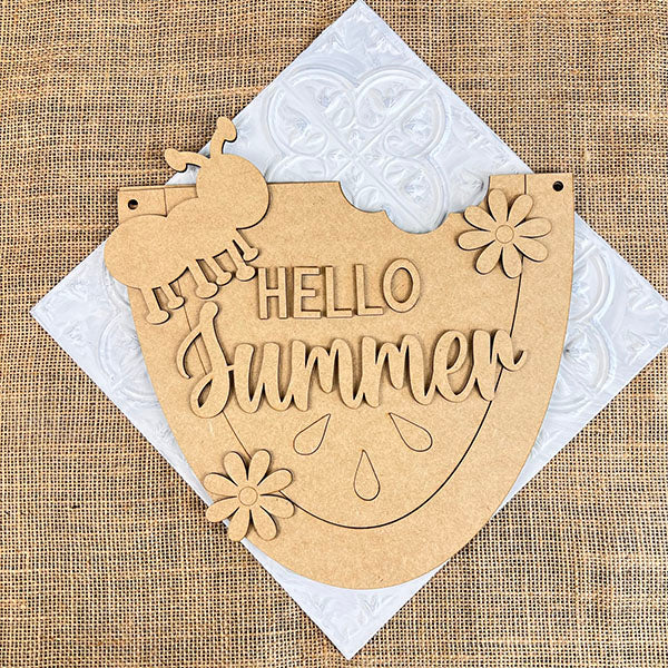 The "Hello Summer" Watermelon Door Hanger from Janet's Craft Corner is perfect for DIY enthusiasts. This wooden sign, shaped like a watermelon slice with an ant cutout and two flowers on a burlap backdrop, serves as ideal summer decor.