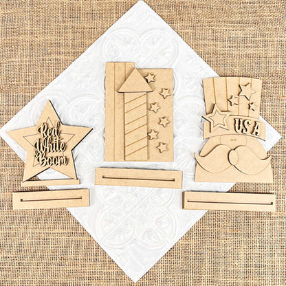 Janet's Craft Corner offers wooden patriotic shelf sitters with burlap details: a star with "Red White Boom," a starry firework, and a hat with "USA" and mustache, each on an embossed white square base. Perfect for farmhouse decor or DIY kits.