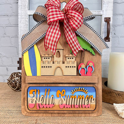 Introducing the Summer Beach Interchangeable Insert, a DIY home decor kit from Janet's Craft Corner. This wooden summer-themed decoration showcases a delightful sandcastle, surfboards, and palm trees, all topped with a red and white checkered bow. The sign displays "Hello Summer" in colorful letters, making it an ideal piece for adding a vibrant touch to your space.