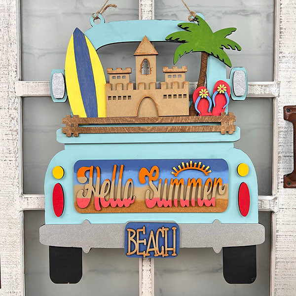 A vibrant truck is decorated with summer-themed accessories: a surfboard, sandcastle, palm tree, and flip-flops. The phrases "Hello Summer" and "Beach" enhance the charm of this hand-painted DIY home decor kit from Janet's Craft Corner. The Summer Beach Interchangeable Insert is perfect as a seasonal decoration piece.