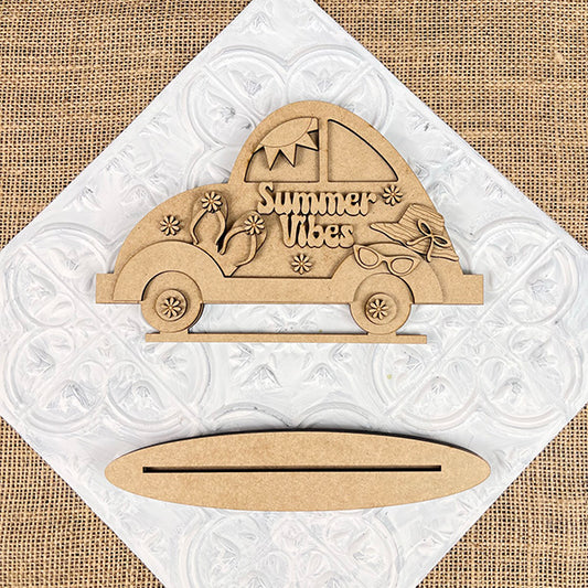 A "Summer Vibes" text-adorned wooden car cutout with summer-themed decorations like sunglasses and a drink, from Janet's Craft Corner, featuring a wooden base with a slot in the foreground. It's the Summer Vibes Volkswagen Shelf Sitter, a DIY home decor craft kit that captures beachy style. Set of 1.