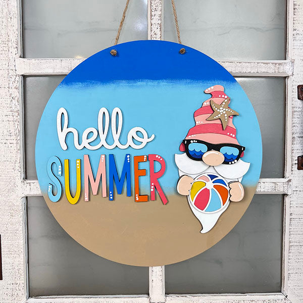 Add a touch of whimsy to your home décor with the "Hello Summer" gnome door hanger by Janet's Craft Corner. This delightful piece features a gnome in sunglasses with a starfish hat, holding a beach ball against a backdrop of blue sky and sandy hues. Enjoy crafting your own summer magic with this fun DIY kit!