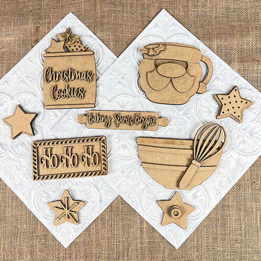 The Vintage Santa Cookies Decor Set by Janet's Craft Corner includes wooden cookie cutters and decorations with designs like "Christmas Cookies," "Baking Spirits Bright," a star, mitten, whisk, and "Ho Ho Ho" on textured white squares over burlap—ideal for creating festive Tiered Tray Sets.