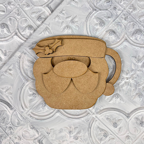 A wooden cup designed as a cutout of Santa's face, featuring a right-side handle, reflects the nostalgic style of Janet's Craft Corner's Vintage Santa Cookies Tiered Tray Set. This delightful piece includes intricate details such as Santa’s holly-adorned hat and mustache set against a textured white background.