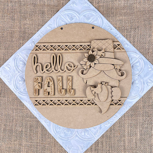 The Hello Fall Gnome Door Hanger from Janet’s Craft Corner features a gnome in a floral hat with pinecone on a burlap background. This DIY kit includes everything needed to create this charming fall door hanger, perfect for seasonal home décor.