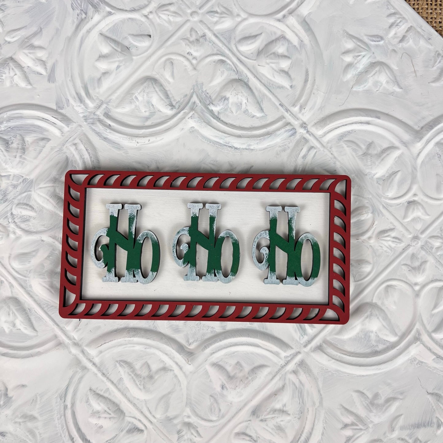 Discover the Vintage Santa Cookies Tiered Tray Set by Janet's Craft Corner, featuring a distinctive rectangular framed art piece. It showcases metallic 3D letters spelling "NO" three times with a striking red border and vibrant green background, ideal for enhancing your DIY kit space. This artistic touch is elegantly displayed on a white, patterned surface.