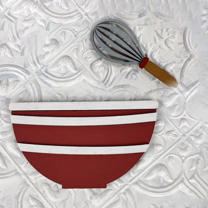 A charming decorative cutout featuring a red mixing bowl with white stripes and a whisk with a brown handle, ideal for enhancing your Vintage Santa Cookies Tiered Tray Set by Janet's Craft Corner, all set against a textured white background.