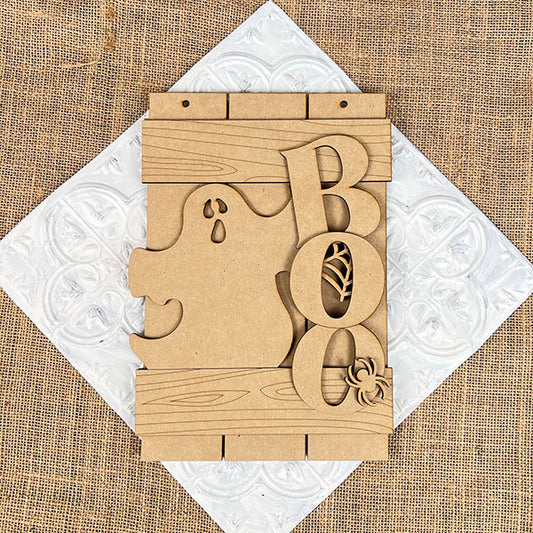 The Boo Fence Door Hanger by Janet's Craft Corner is a DIY décor kit featuring the word "BOO" with a ghost cutout and spider details against a burlap-like backdrop, perfect for adding craft flair to your Halloween festivities.