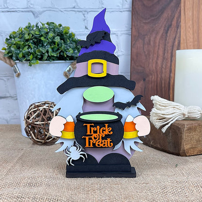 The Witch Gnome from Janet's Craft Corner is a charming addition to your Halloween home décor. It features a whimsical figure wearing a purple witch hat and holding a "Trick or Treat" cauldron overflowing with candy corn. Adorned with black bats and a white spider, this enchanting DIY kit comes to life against a rustic backdrop, complemented by the presence of a potted plant.