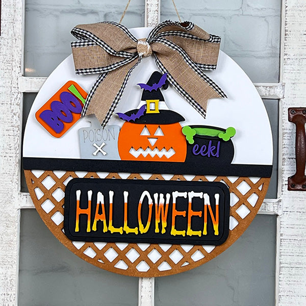 Introducing the Halloween Pumpkin Interchangeable Insert from Janet's Craft Corner, a perfect addition to your DIY home decor kit. This round door sign showcases a charming pumpkin wearing a witch hat, a cauldron that exclaims "eek!", and the bold word "BOO!" A delightful bow adorns the top, while "HALLOWEEN" elegantly spans across the lattice bottom, making it ideal for festive interchangeable craft inserts.