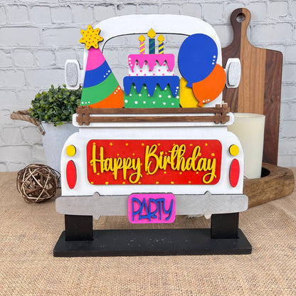 Introducing the Birthday Interchangeable Insert from Janet's Craft Corner—an eye-catching festive decoration shaped like a car. It features a "Happy Birthday" sign, vibrant balloons, and a tiered cake on top, with the tailgate adorned with bright "PARTY" letters. This part of a versatile DIY home decor kit is ideal for enhancing any craft project.