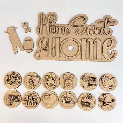 Janet's Craft Corner offers the "Home Sweet Home Interchangeable Set Shelf Sitter" DIY kit, featuring a laser-cut wooden sign and 12 detachable plaques with festive designs like a bunny, turkey, and Christmas tree.