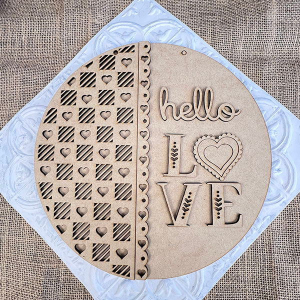 The Hello Love Round Sign from Janet's Craft Corner is a laser-cut wooden decoration featuring hearts, stripes, and "hello LOVE," with a heart for the "O." Ideal as home decor or part of your DIY kit, it adds charm to any space.