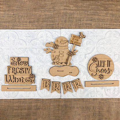 The Let It Snow Decor Set by Janet's Craft Corner is a winter-themed DIY home decor craft kit featuring 6 wooden pieces, including a snowman with a flag and snowflake motifs. With phrases like "Snow Frosty Winter" and "Let it Snow," they're perfect for your home or tiered tray displays and are easy to assemble.