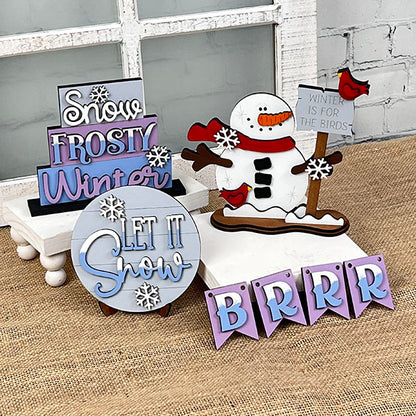 Create a festive atmosphere with the Let It Snow Tiered Tray from Janet's Craft Corner. This winter-themed display includes a charming snowman design, a "Winter is for the birds" sign, delicate snowflakes, and pastel signs with messages such as "Snow Frosty Winter," "Let it Snow," and "BRRR" on burlap, adding an enchanting touch to your holiday décor.