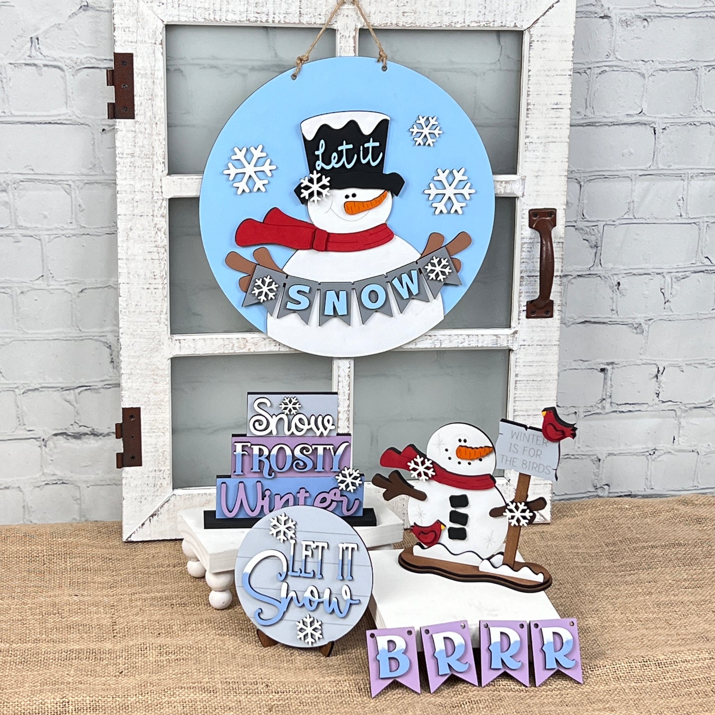 Introducing an enchanting selection of holiday decorations from Janet's Craft Corner, including the "Snowman Let It Snow" door hanger, delightful signs reading "Snow" and "Frosty Winter," and a cute snowman sledding with the phrase "Winter is for Sledding." These pieces are perfect for adding a touch of whimsy to your DIY kit.