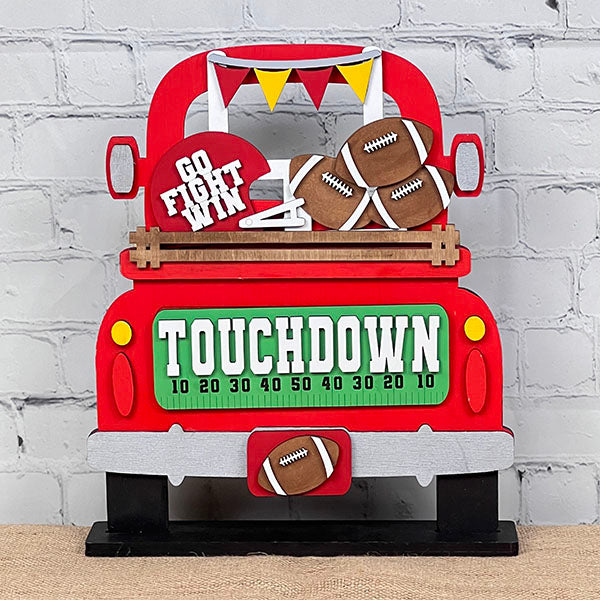 Introducing the Football Interchangeable Insert DIY home decor kit by Janet's Craft Corner: This charming red truck set showcases football-themed accents, including interchangeable footballs, helmets with "Go Fight Win," a goalpost, and a "Touchdown" sign. Perfectly set against a white brick wall backdrop, it offers an ideal project for hand-painted DIY craft enthusiasts looking to add a personal touch to their decor.