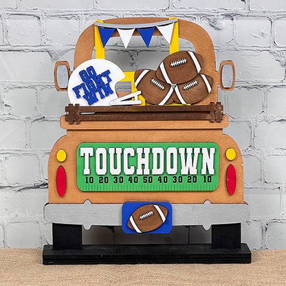 Introducing Janet's Craft Corner's "Football Interchangeable Insert," a DIY home decor kit featuring a decorative wooden cutout of a truck's rear filled with football-themed items like helmets, footballs, and a banner. This hand-painted craft includes the word "TOUCHDOWN" on the truck's tailgate with yard lines marked in tens, making it an ideal interchangeable decor piece for your home.