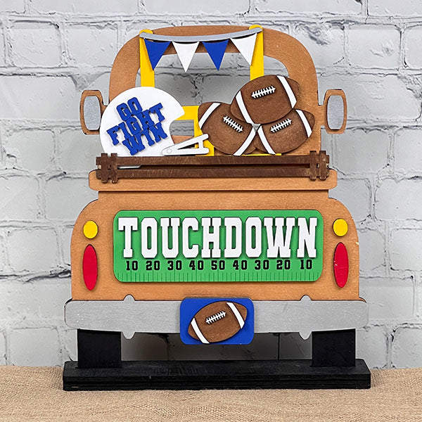 The Antique Truck Base with Insert by Janet's Craft Corner is a DIY kit featuring a football-themed wooden sign shaped like an antique truck bed. It includes elements like a white helmet with "Go Fight Win," footballs, pennant flags, and "TOUCHDOWN" on the tailgate for enthusiasts of stylish home décor.