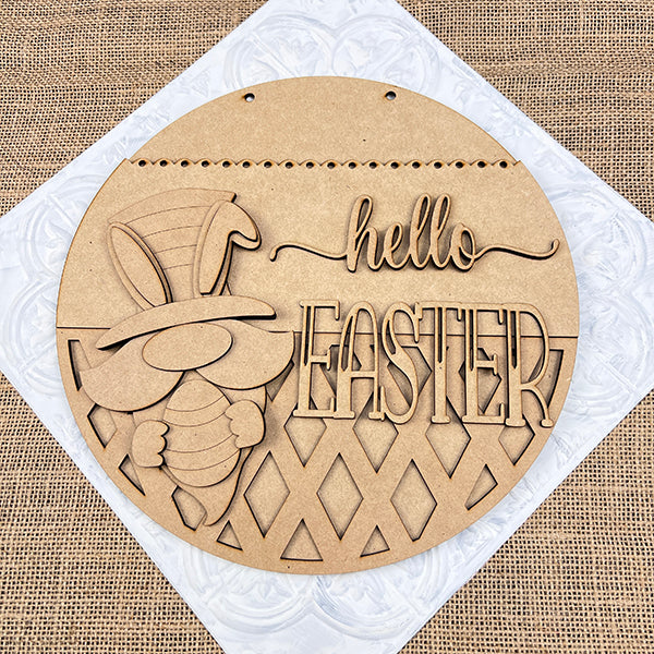 The Hello Easter Gnome Wall Hanger from Janet's Craft Corner is a DIY decor craft kit featuring a laser-cut bunny with an egg and top hat. Set against textured brown fabric, it's perfect for adding seasonal flair to your home.