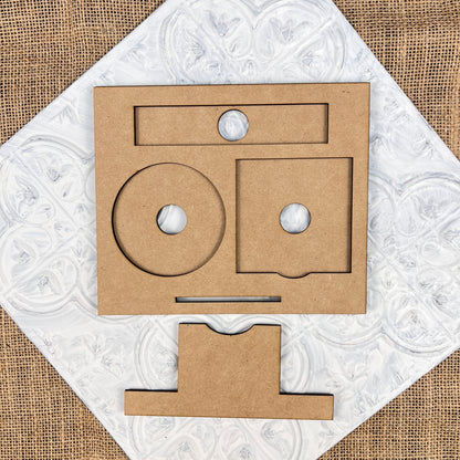 Cardboard geometric shapes from Janet's Craft Corner are artfully arranged on a textured white surface, resembling abstract facial features. This Desk Post-It Note Holder Interchangeable Set includes circles, squares, and rectangles set against a burlap background, making it ideal for crafting your own desk organizer.