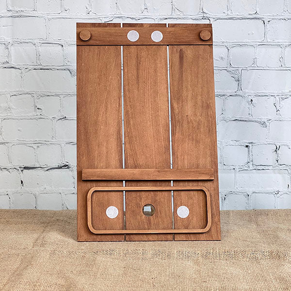 The Pallet Interchangeable Base with Insert - Painted by Janet's Craft Corner features a wooden game board with a vertical stand, circular white markers, horizontal bar, and rectangular target area, shown against a white brick wall.