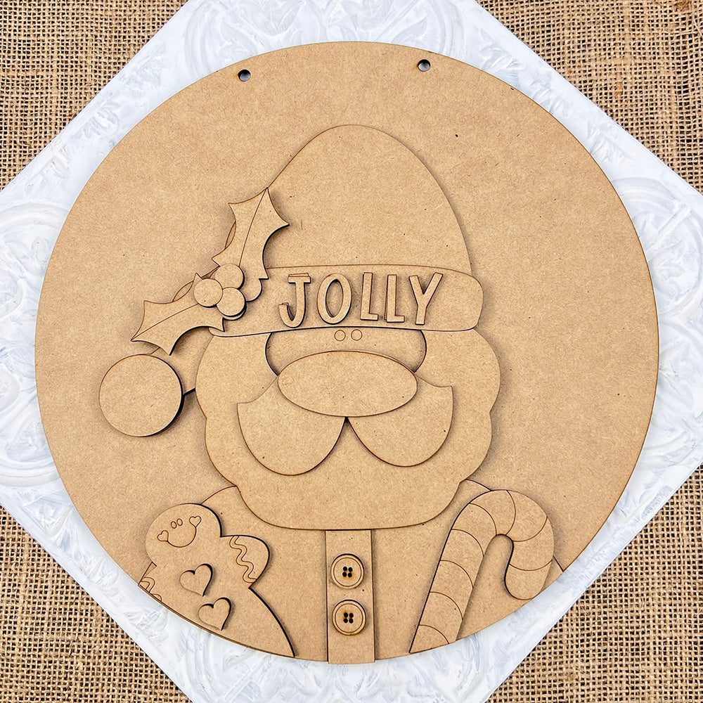 The Jolly Santa Round Sign from Janet's Craft Corner is a delightful holiday decoration. This DIY Home Decor Kit features a wooden cutout of Santa with "Jolly" on his hat, highlighted by holly accents. Santa holds a gingerbread man and candy cane against a burlap-textured background, making it an ideal choice for your hand-painted craft project!