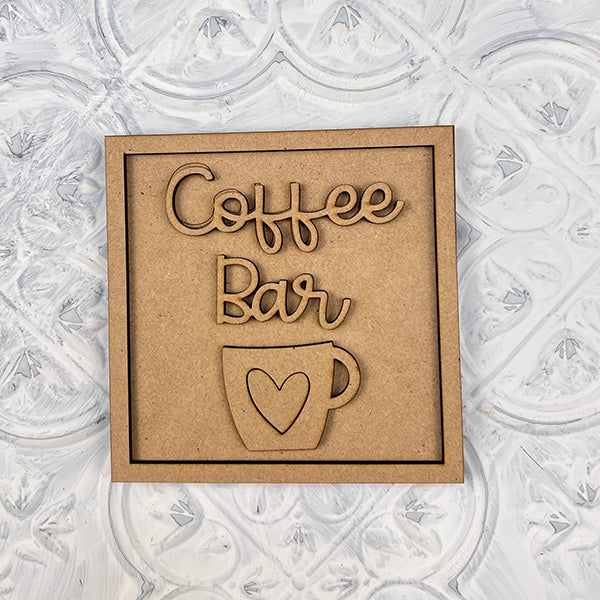 The Coffee Swappable Squares DIY craft kit from Janet's Craft Corner features a wooden sign with "Coffee Bar" above a coffee cup with a heart—perfect for your next coffee-inspired project or seasonal home decor makeover.