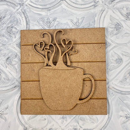 Janet's Craft Corner Coffee Swappable Squares is a DIY seasonal home decor craft kit featuring a wooden coffee mug cutout with heart steam, set on a square slatted background—ideal for coffee lovers and creative projects.