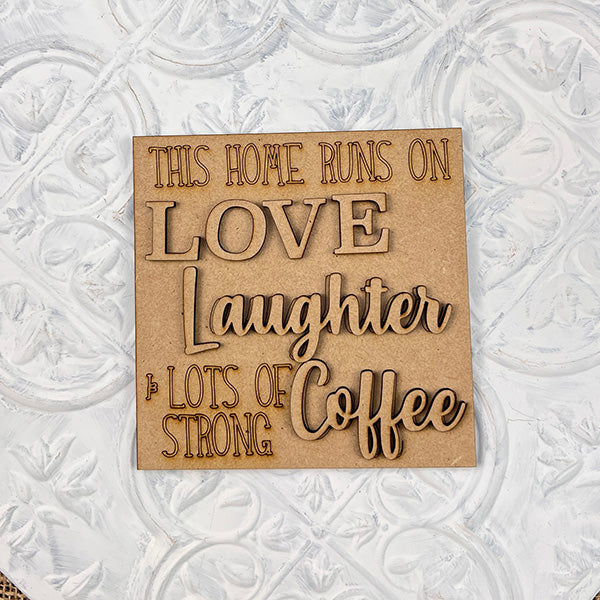 The Coffee Swappable Squares DIY kit from Janet's Craft Corner features a wooden sign with engraved text: "This home runs on love, laughter & lots of strong coffee," ideal for seasonal home decor with a cozy, coffee-inspired touch.