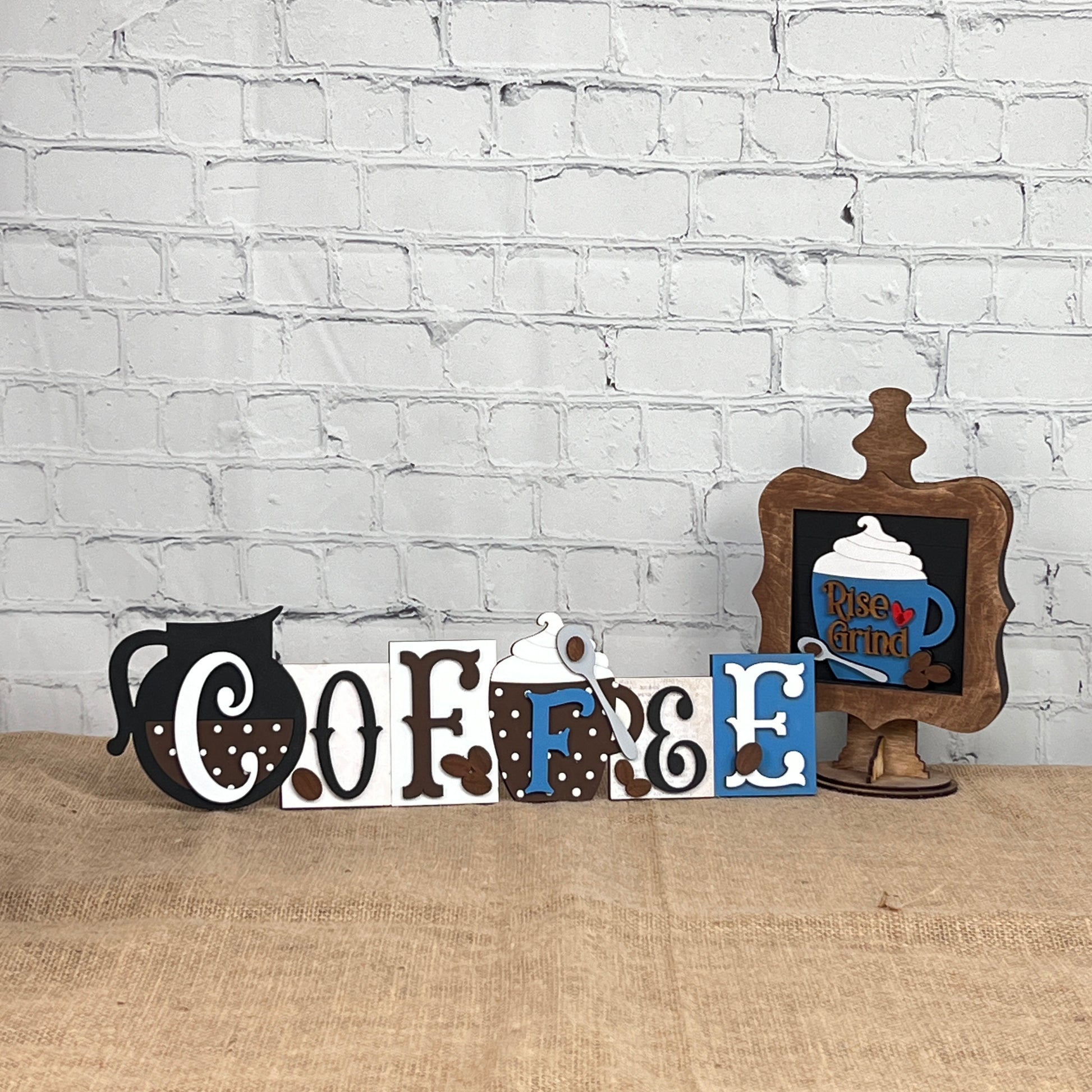 Janet's Craft Corner Coffee Squares feature decorative wooden letters that spell "COFFEE" with coffee-themed designs, plus a sign with a dark blue mug and "Rise & Grind," creating charming seasonal decor for small spaces.