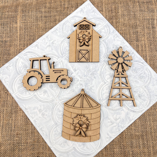 The Farm Life Christmas Ornaments - Set of 4 from Janet's Craft Corner, featuring a tractor, barn, silo, and windmill, capture the essence of farm life. Displayed on a textured white square with a burlap background, these ornaments can be utilized as part of a DIY Decoration Kit or as delightful Christmas decorations for your festive setting.