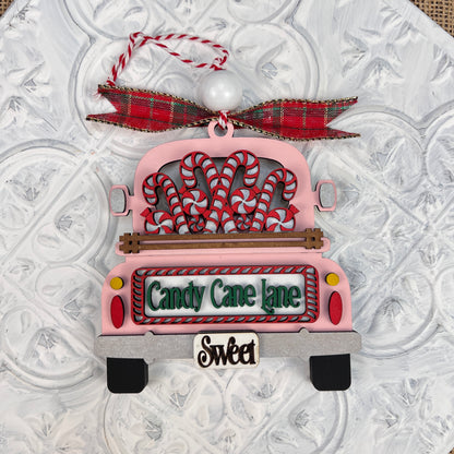 Add a delightful touch to your holiday season with Janet's Craft Corner's Antique Truck Ornament, an exquisite DIY decoration kit. This charming Christmas piece features a pink antique truck adorned with candy canes and topped with a red plaid bow. The back reads "Candy Cane Lane" and "Sweet," all set against a textured white background.