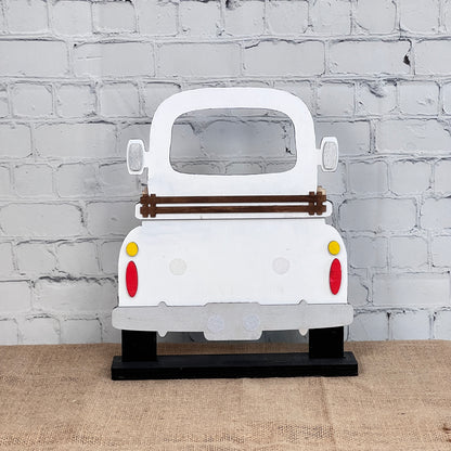 The Antique Truck Interchangeable Base - Painted from Janet's Craft Corner is a wooden white vintage truck cutout with red and yellow taillights on a black stand, ideal for mantel or craft displays.