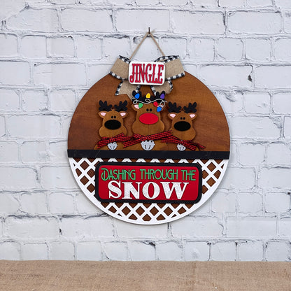 Add festive cheer with Janet's Craft Corner's Reindeer Interchangeable Insert. This DIY seasonal home decor kit features hand-painted reindeer with red noses and scarves, a plaid "Jingle" sign above, and "Dashing Through the Snow" below, set against a white brick wall.