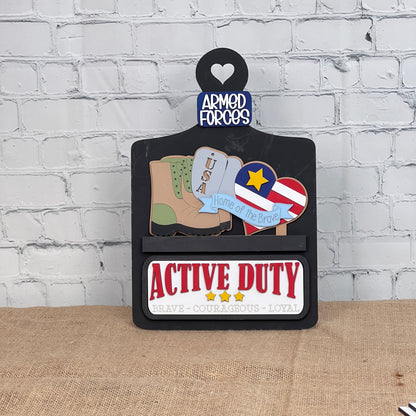 Janet's Craft Corner presents the Military Interchangeable Insert—a DIY home decor kit featuring stylized military boots, USA dog tags, and a medal. A heart reads "ARMED FORCES," while burlap-textured text states "ACTIVE DUTY" and "BRAVE - COURAGEOUS - LOYAL.