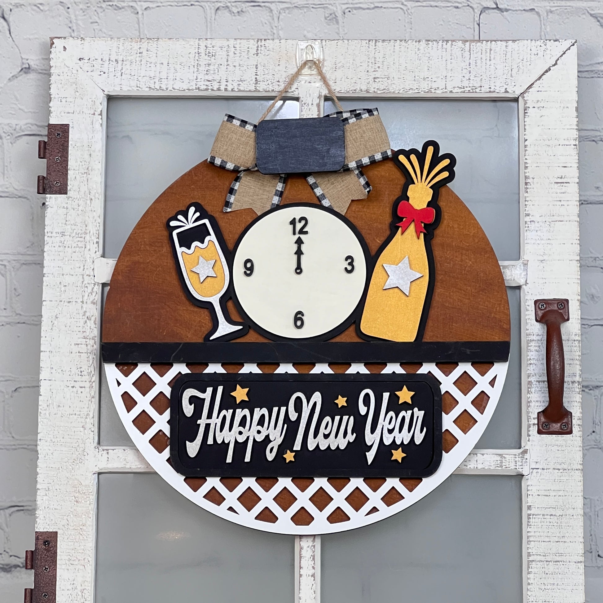 Customize your door with Janet's Craft Corner's New Year Interchangeable Insert. This DIY home decor craft kit includes 3 pieces: a clock nearing midnight, a champagne glass, and "Happy New Year" in white and gold, adorned with a plaid bow. Perfect for adding festive cheer!.