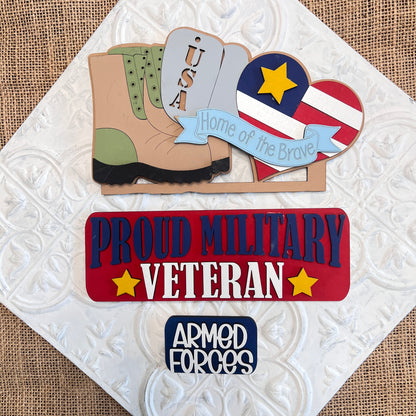 Janet's Craft Corner offers a Military Interchangeable Insert set, featuring burlap signs: a USA boot, a stars-and-stripes heart, and a "Proud Military Veteran" plaque. This DIY home decor kit adds patriotic charm to any space.