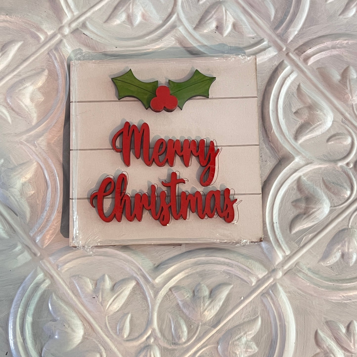 The Christmas Mini Shelf Sitters by Janet's Craft Corner feature red "Merry Christmas" text with a green holly and red berries above, all set on a white textured background with ornate patterns.