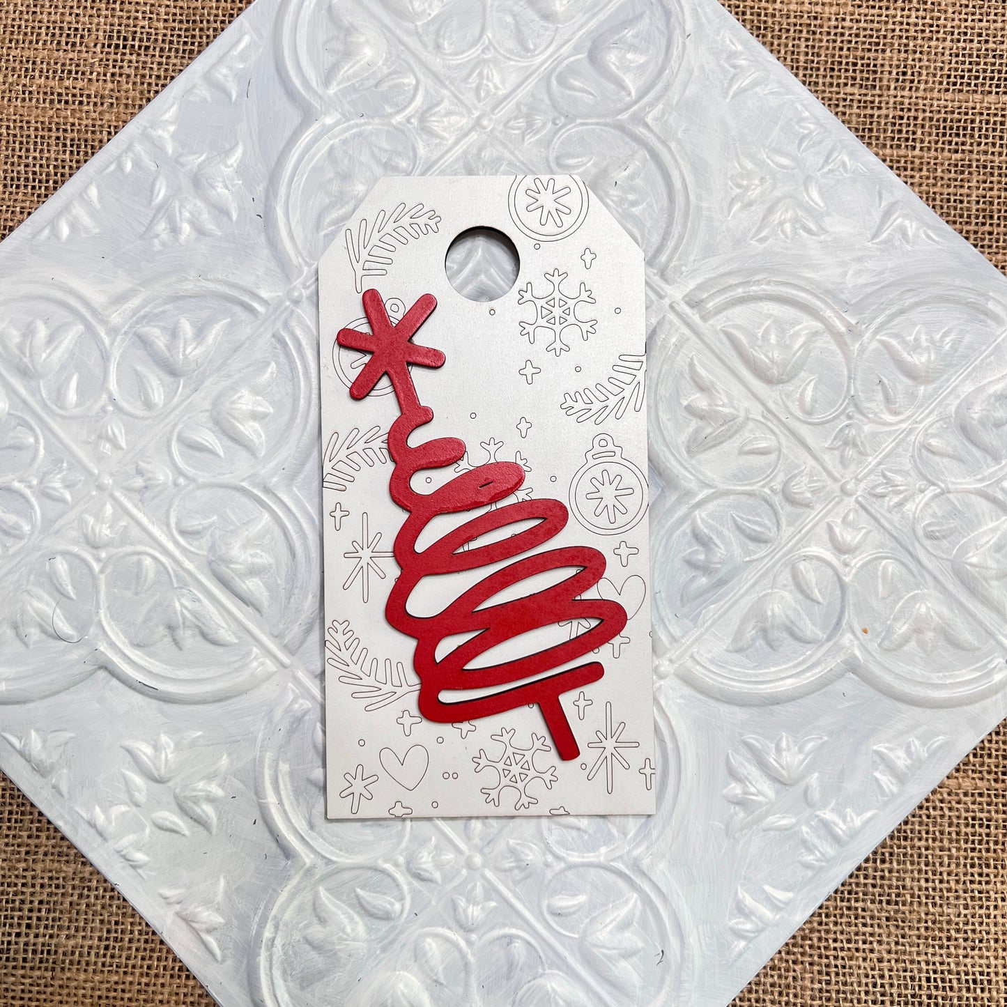 The Christmas Mini Shelf Sitters from Janet's Craft Corner feature a red, abstract spiral tree with a star on top, set against white with silver holiday doodles, displayed on a textured tile.
