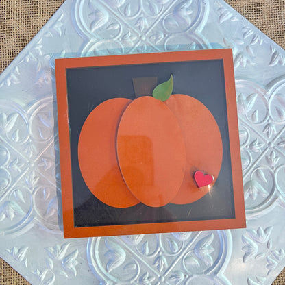 Janet's Craft Corner 6 inch squares feature a handmade card with a pumpkin of orange ovals, brown stem, green leaf, and a red heart, set on a silver embossed background.