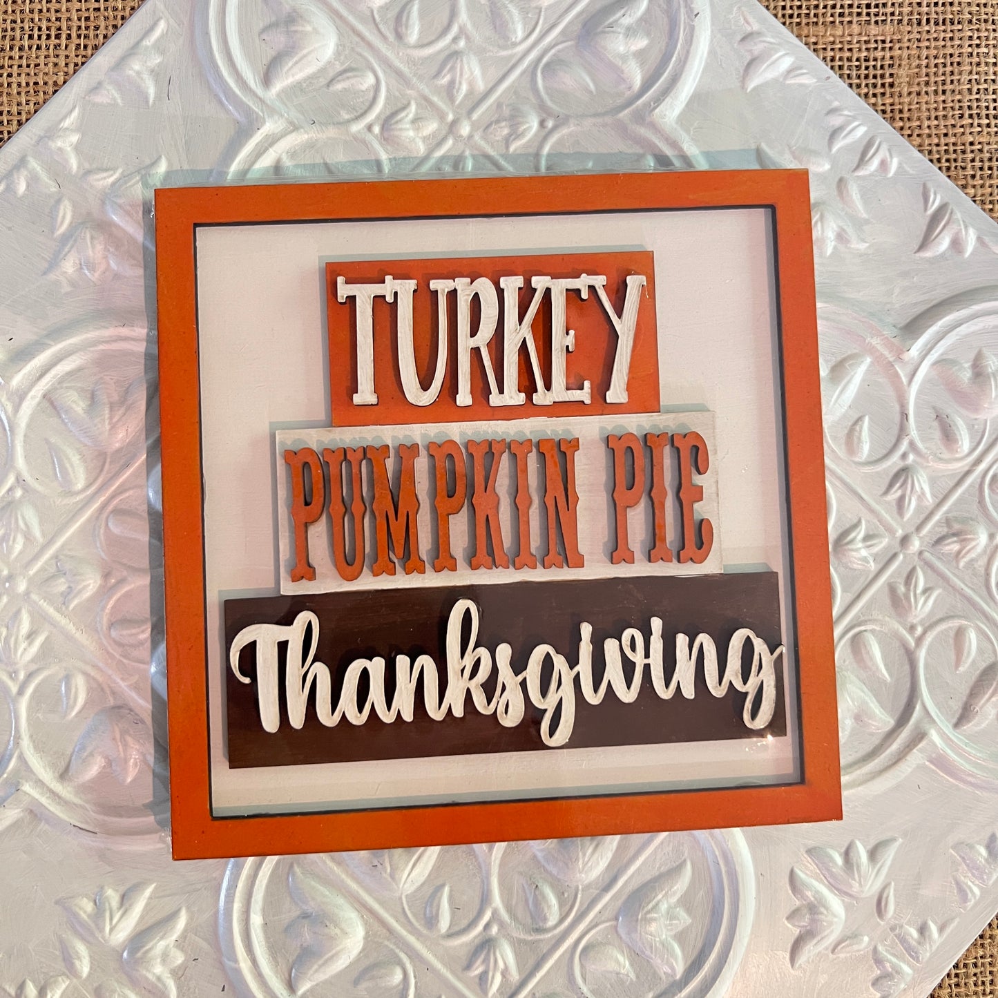 Janet’s Craft Corner 6 inch squares feature orange and brown blocks displaying “Turkey,” “Pumpkin Pie,” and “Thanksgiving” in white and orange letters, all set against a textured white background.
