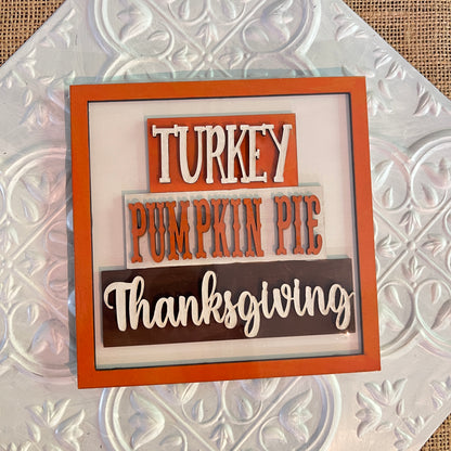 Janet’s Craft Corner 6 inch squares feature orange and brown blocks displaying “Turkey,” “Pumpkin Pie,” and “Thanksgiving” in white and orange letters, all set against a textured white background.