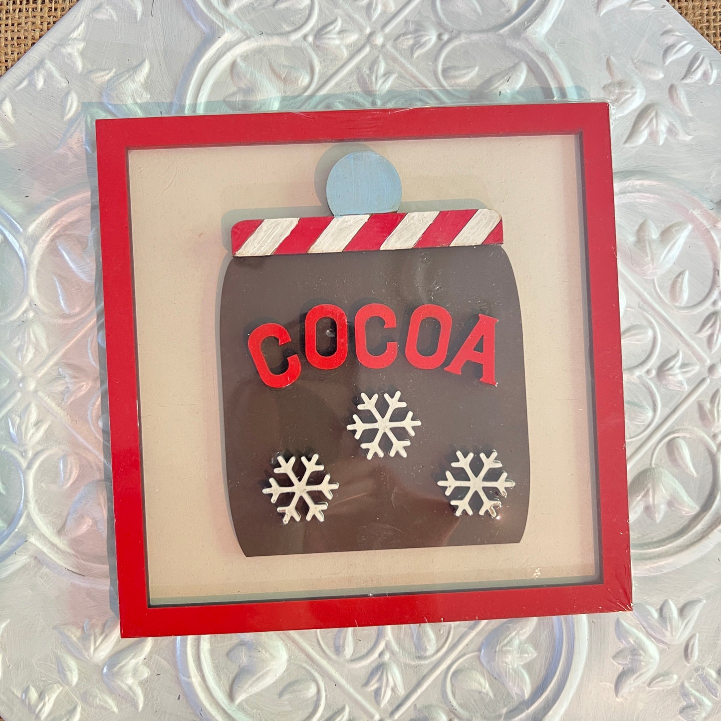 Janet's Craft Corner 6 inch square sign features a red-bordered frame with a silver textured background, a mug labeled "COCOA" in red letters, three white snowflakes, and a candy cane striped rim.