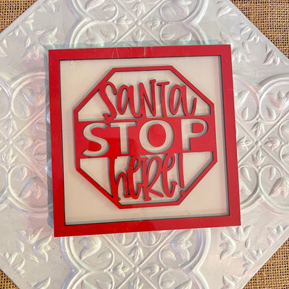 A red and white stop sign-shaped decor from Janet's Craft Corner features playful "Santa STOP here!" lettering, displayed on their 6 inch squares with a white textured background.