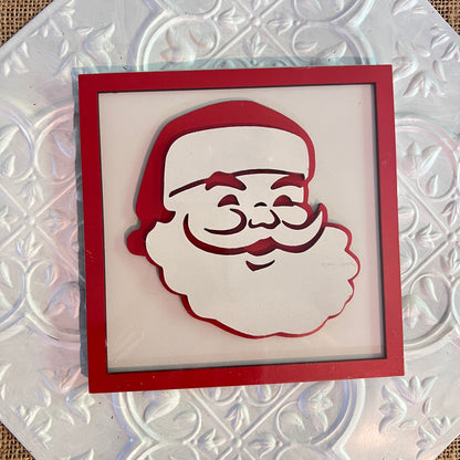 A 6 inch square from Janet's Craft Corner features Santa Claus’s smiling face—complete with hat, mustache, and beard—on a red and white embossed background.