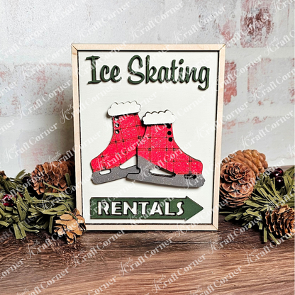 The Ice Skating Rentals Interchangeable Sign by Janet's Craft Corner showcases red ice skates and text on a scenic backdrop of pine cones, greenery, and a wooden surface with a hint of brick wall, ideal for home decor lovers.