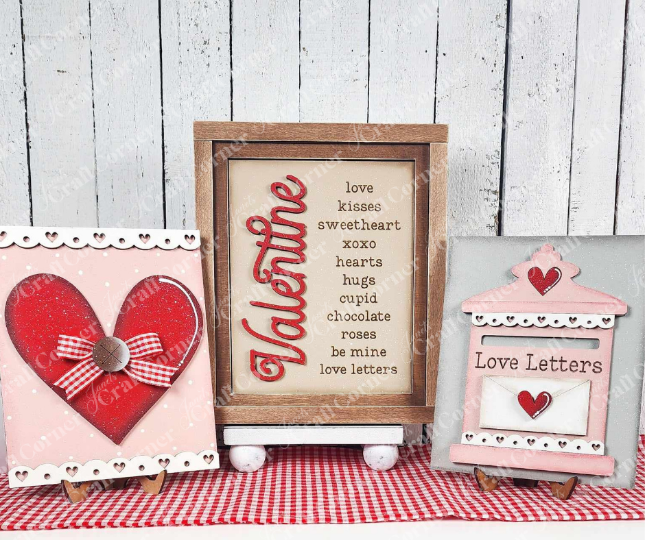 Celebrate Valentine's Day with Janet's Craft Corner's "Valentine Words Sign." This charming DIY set features a trio of hand-painted signs: one with a red heart, another with "love" and "kisses," and a third resembling a mailbox labeled "Love Letters" against a rustic white wood background.